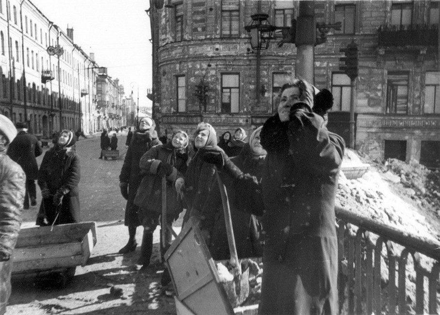 Женщины, занятые уборкой ленинградских улиц, наблюдают за воздушным боем над городом